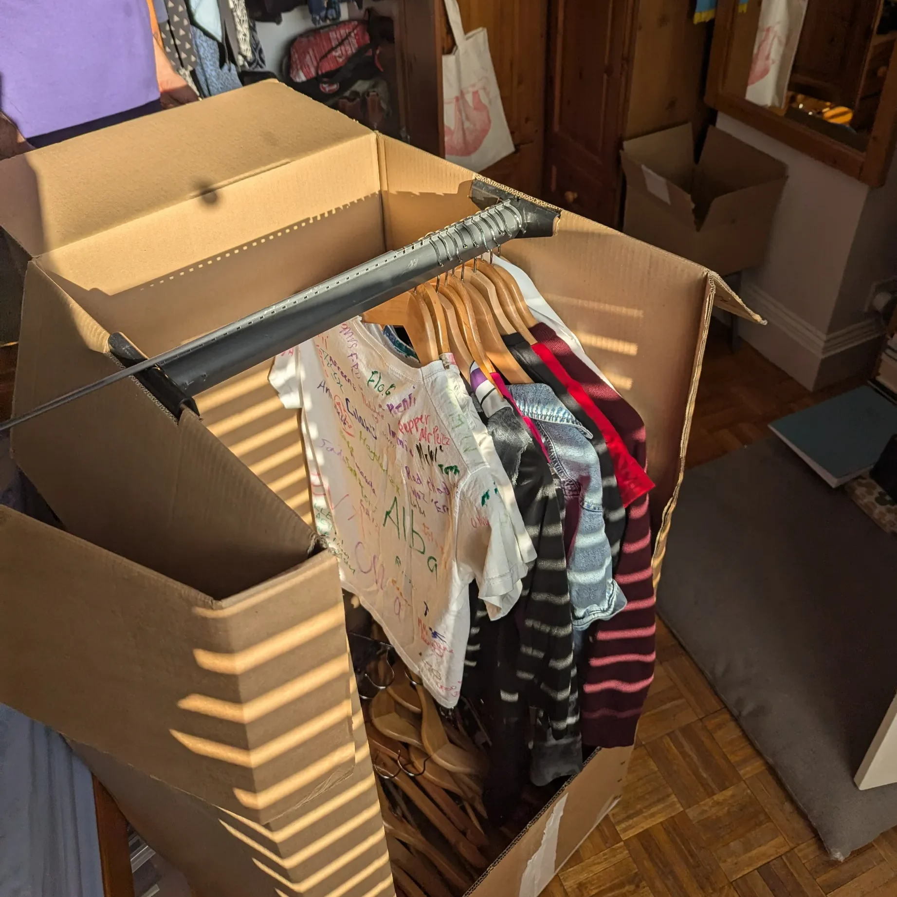 Open wardrobe box showing neatly hung clothes on a rail packed by Rad Removals